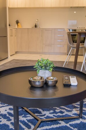 A round table with three metallic bowls, a small potted plant, and two remote controls. - Groveview Oasis: 1BR Retreat (Lower Hutt)