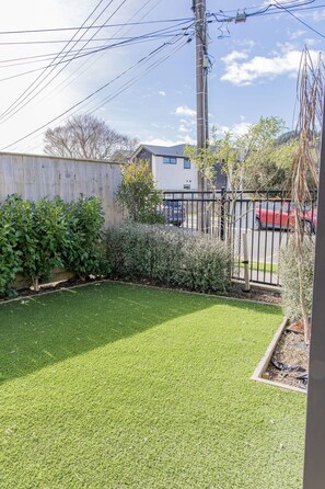 A residential backyard with a well-maintained lawn, a wooden fence, and a metal gate.
