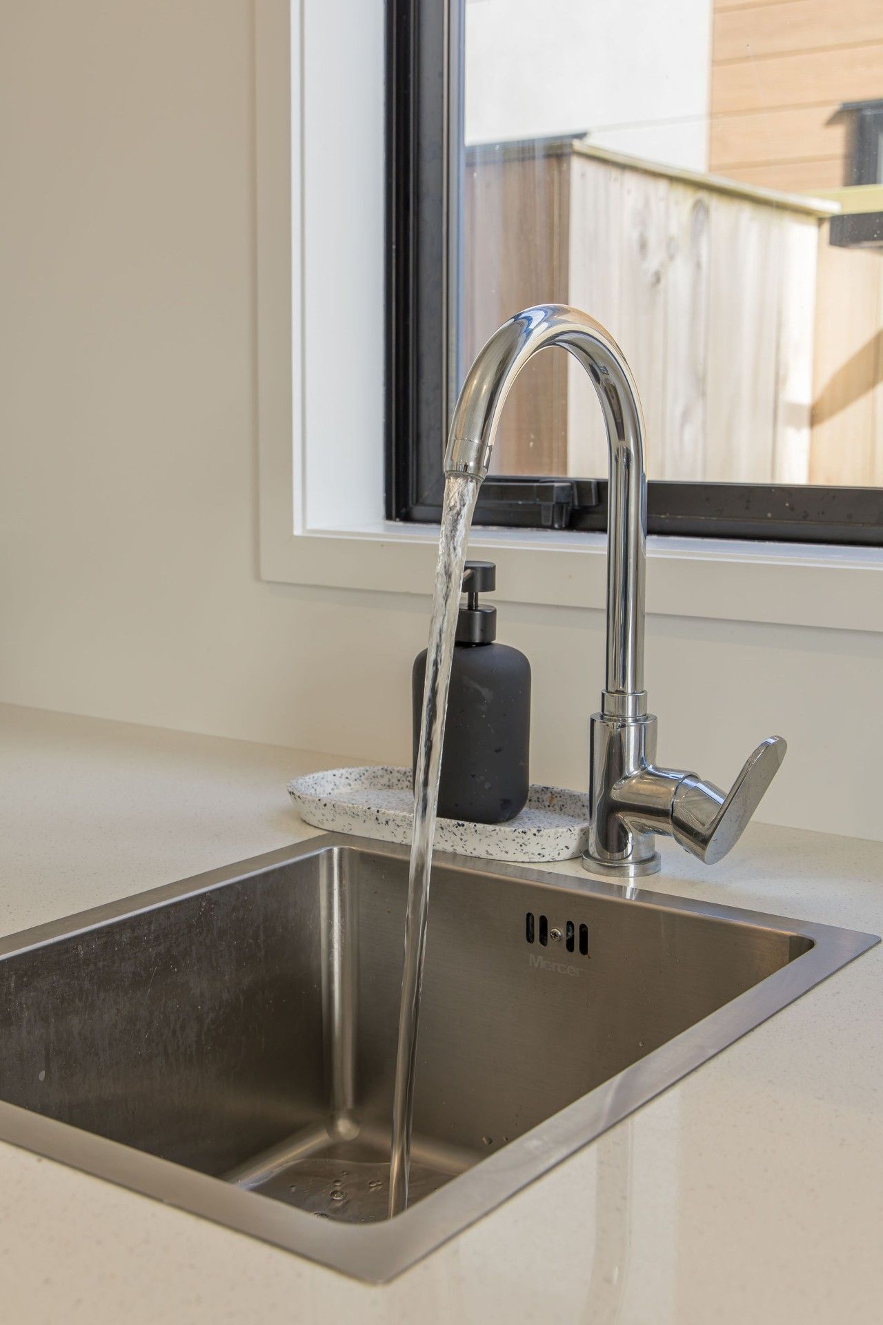 A stainless steel kitchen sink with a modern faucet and soap dispenser.