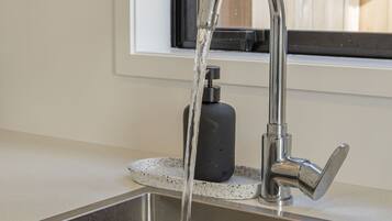 A stainless steel kitchen sink with a modern faucet and soap dispenser.