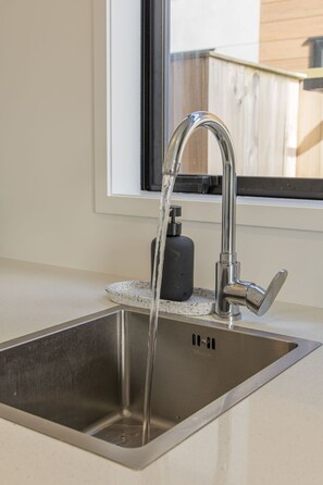 A stainless steel kitchen sink with a modern faucet and soap dispenser.