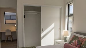 A hotel room with a bed, a desk, a chair, a lamp, and a window. - Retreat at Biddle Crescent (Lower Hutt)