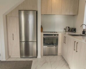 A modern kitchen with a stainless steel refrigerator, oven, and a built-in stovetop.