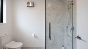 Ein modernes Badezimmer mit Toilette, einer Duschkabine mit Glastür und einem Marmorboden.