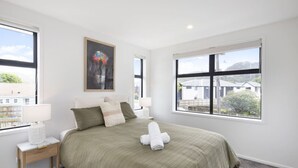Ein Schlafzimmer mit einem großen Bett, zwei Nachttischen, einem Fenster mit Blick und einem Bild an der Wand.