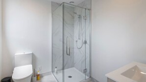 A modern bathroom with a glass-enclosed shower, a white toilet, and a bathtub. - Biddle Cres Elegance (Lower Hutt)