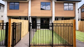 A modern two-story residential building with a flat roof, large windows, and a gated entrance. - The Biddle Haven: 2BR Retreat (Lower Hutt)