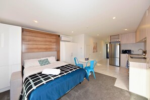 Una habitación de hotel moderna con cama, escritorio y kitchenette.