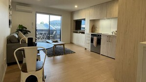 Un apartamento moderno con comedor, cocina y puerta corrediza de vidrio que da a un balcón.
