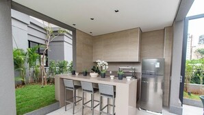 A modern kitchen with a built-in island, bar stools, a refrigerator, and potted plants. - Fully equipped studio WiFi, AC Sao Paulo metro Sacoma Paulista Congonhas Airport (São Paulo)