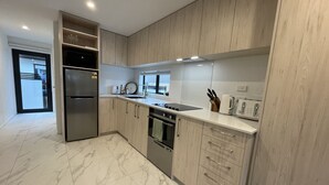 Une cuisine moderne avec des meubles en bois clair, des appareils en acier inoxydable et un sol en marbre.