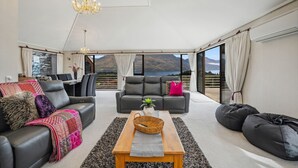 Ein großzügiges Wohnzimmer mit einem großen Fenster und Blick auf die Berge, einer Kristallleuchter und einer gemütlichen Sitzecke mit Couchtisch.