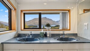 Ein Badezimmer mit zwei Waschbecken, einem Fenster mit Bergblick und einem Spiegel.