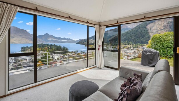 Ein geräumiges Zimmer mit großem Balkon und herrlicher Aussicht auf einen See und Berge.
