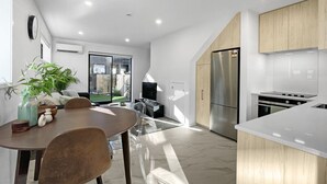 Una cocina moderna con comedor, que cuenta con una isla grande, electrodomésticos de acero inoxidable y vistas al exterior.