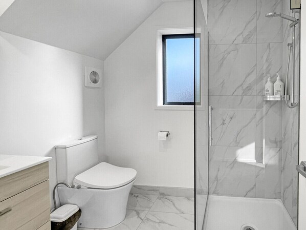 A modern bathroom with a toilet, a shower, and a window. - Wilmer Street City Stay (Christchurch)