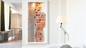 A modern living room with a white sofa, a lamp, and a brick wall feature.