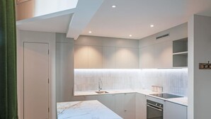 A modern kitchen with a marble countertop, built-in oven, and a window above the sink.