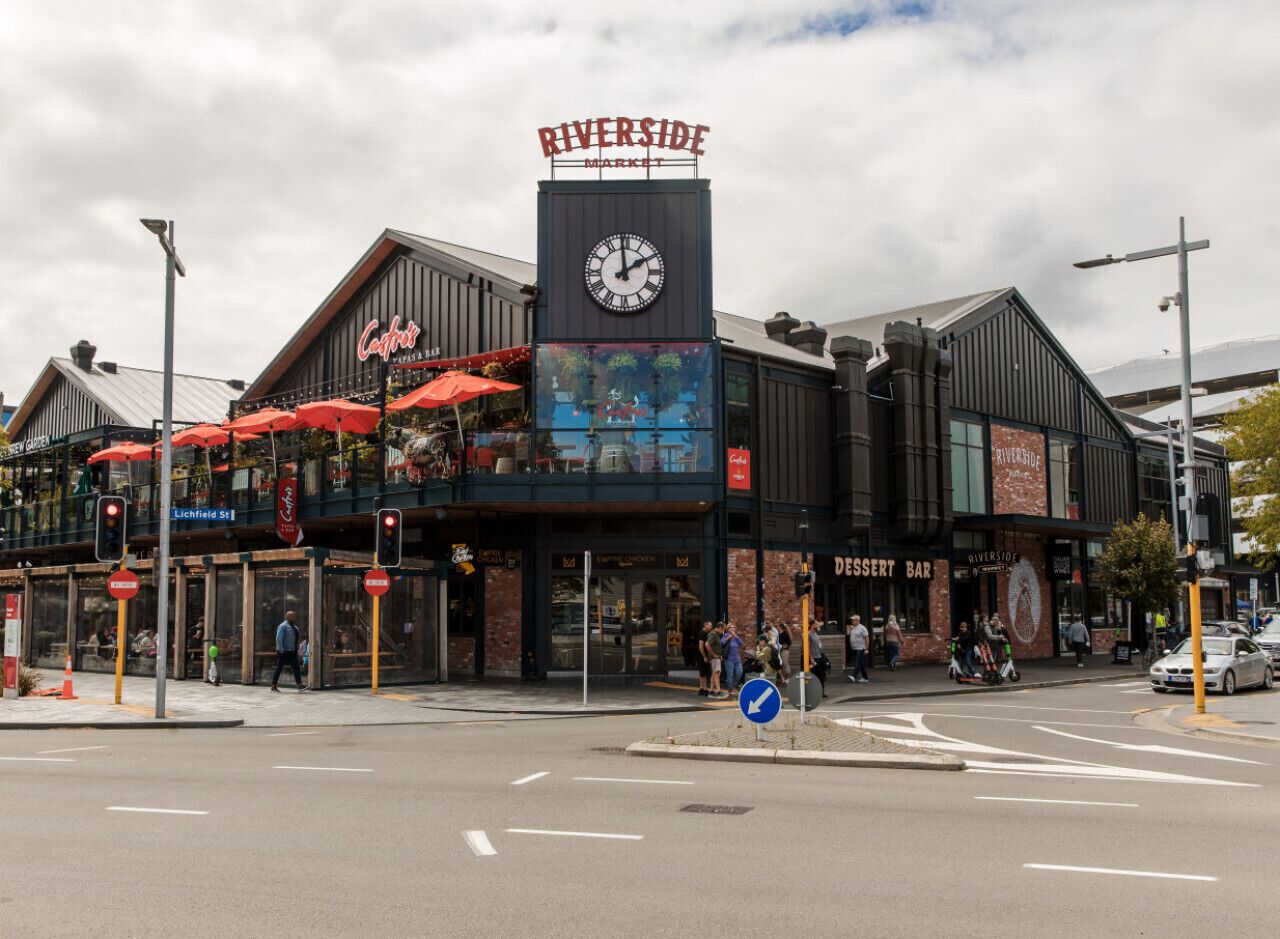 A Riverside Market building with a clock, outdoor seating, and a dessert bar.