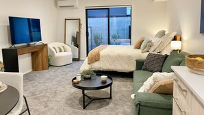 A modern living room with a bed, a sofa, a coffee table, and a TV. - Cosy Studio in Allen Street (Christchurch)