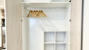 A walk-in closet with a wooden finish, featuring open shelves and hanging space. - Cosy Studio in Allen Street (Christchurch)