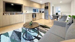 Eine moderne Küche mit Holzschränken, einem eingebauten Ofen und einem großen Fernseher.