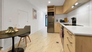 Una cocina moderna con piso de mármol, gabinetes de madera, horno empotrado y un comedor con mesa y sillas.