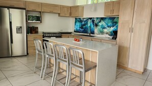 Una cocina moderna con armarios de madera, un refrigerador de acero inoxidable, una estufa integrada y una isla grande con taburetes de bar.