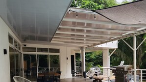 Un espacio exterior cubierto con piscina, mobiliario y zona de barbacoa.