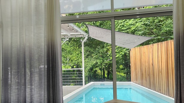 Una habitación con un ventanal grande, un escritorio de madera y vistas a una piscina.