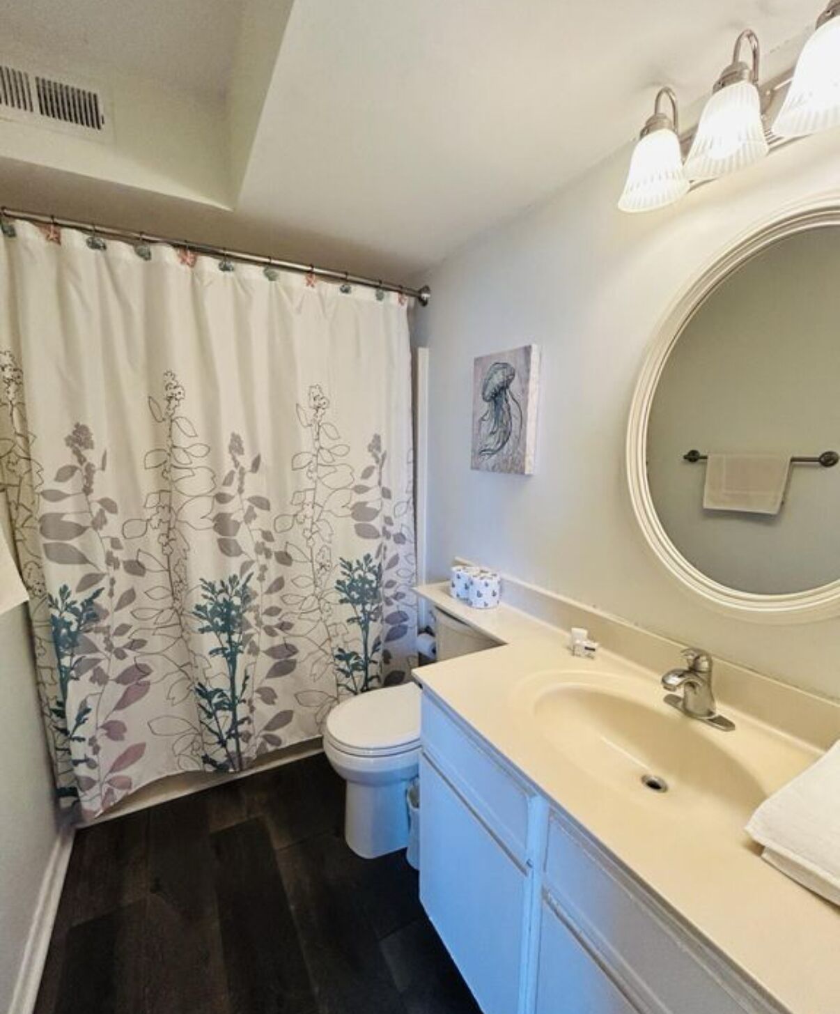 A bathroom with a toilet, sink, and shower curtain with floral patterns.