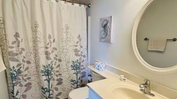 A bathroom with a toilet, sink, and shower curtain with floral patterns.
