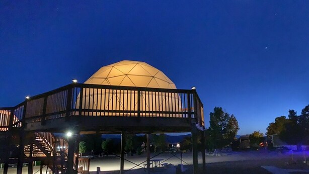 A dome-shaped building with a wooden deck and stairs leading up to it.