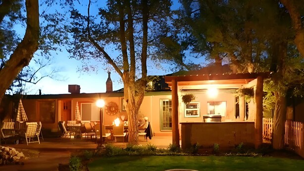 A cozy backyard with a dining area, a small garden, and a well-lit building. - Family-Friendly Cabin with Fire Pit, BBQ, Picnic Area, and Free Parking (Cañon City)