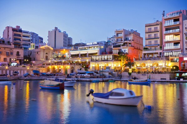 A waterfront area with boats docked, buildings, and a prominent Dolce Vita restaurant. - Modern 2BR Escape in St Julians (Saint Julian's)