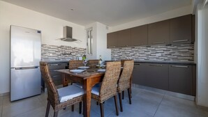Una cocina moderna con comedor, que cuenta con un refrigerador de acero inoxidable, horno empotrado y salpicadero de azulejos.