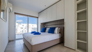 Un dormitorio moderno con una cama grande, armario empotrado y vistas a la ciudad.