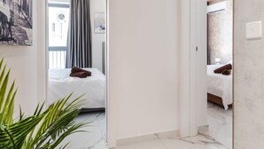 A hallway with a bed, a potted plant, and a door leading to another room. - Stylish 2BR Escape in St Julians (Saint Julian's)