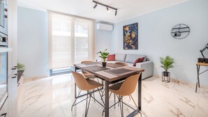 A modern living room with a dining table, sofa, and two potted plants. - Stylish 2BR Escape in St Julians (Saint Julian's)