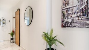 A hallway with a marble floor, a wooden door, a round mirror, and a potted plant. - Stylish 2BR Escape in St Julians (Saint Julian's)