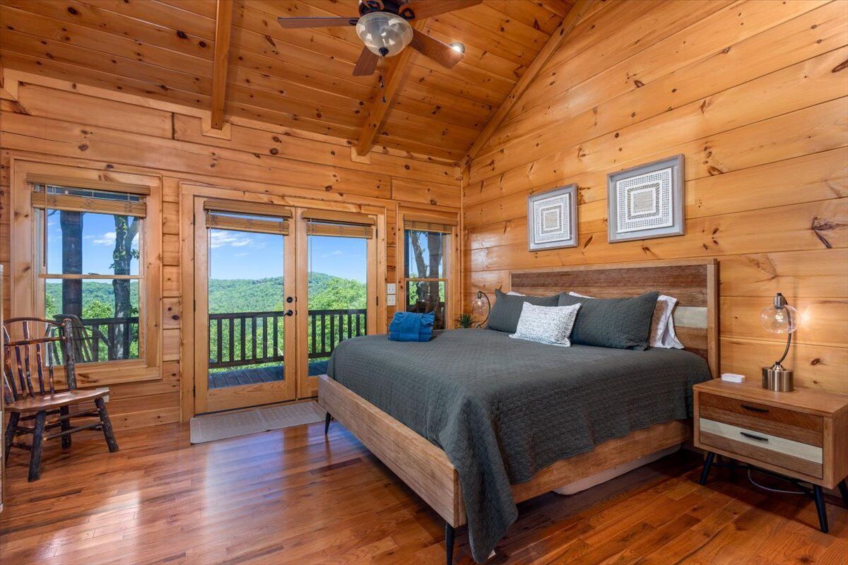 Dormitorio de una cabaña de madera con una cama, mesita de noche y vistas al exterior.