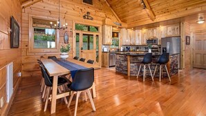 A wooden cabin interior with a dining area, kitchen, and a stone island. - Newly renovated  5BR 3BA Cabin with amazing Mountain Sunset views (Morganton)