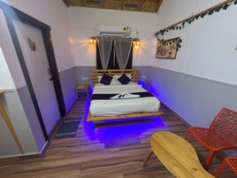A small, cozy room with a bed, a nightstand, a wooden bench, and a red chair.