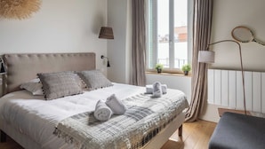 A neatly made bed with a plaid blanket, a bedside lamp, and a tennis racket on the wall. - Dify Art Deco - Charpennes (Villeurbanne)