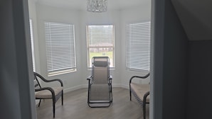 A room with three wicker chairs, a central exercise bike, and large windows with blinds. - Enchanting 4-bedroom house with AC in Cleveland (Cleveland)