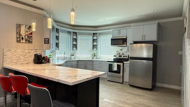 A modern kitchen with a central island, stainless steel appliances, and a breakfast bar with red chairs. - Enchanting 4-bedroom house with AC in Cleveland (Cleveland)