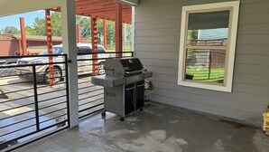 A covered patio area with a barbecue grill, a window with a view of a backyard, and a gated entrance. - Enchanting 4-bedroom house with AC in Cleveland (Cleveland)
