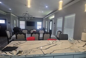 A modern dining area with a Galaxy S24 Ultra table, a chandelier, and a ceiling fan.