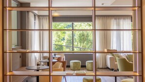 Una sala de estar moderna con piso de madera, un juego de sofá, una mesa de comedor con sillas y un ventanal con cortinas.