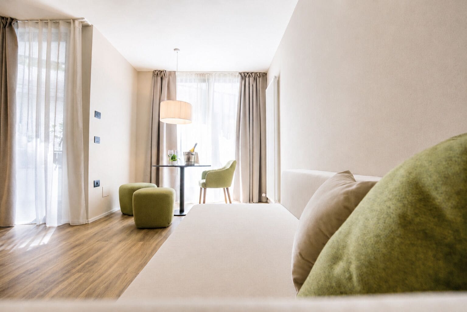 Habitación de hotel con cama, una mesita de noche con lámpara, una silla y vistas al exterior.